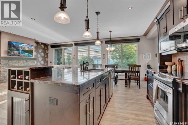 Entranceway with a glass door, dark tiled floor, bench, and a large window. - 4635 Ellard Court, Regina