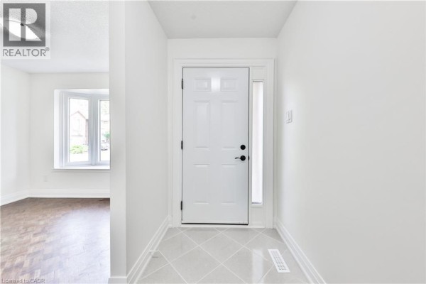 Entrance foyer with a white front door, side window, and light grey tiled floor. - 4635 Regents Terrace Unit# 2, Mississauga