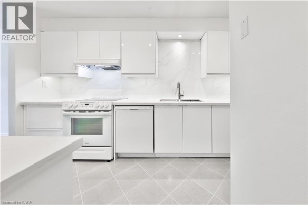 Modern white kitchen with glossy cabinets, white countertops, and stainless steel appliances. - 4635 Regents Terrace Unit# 2, Mississauga