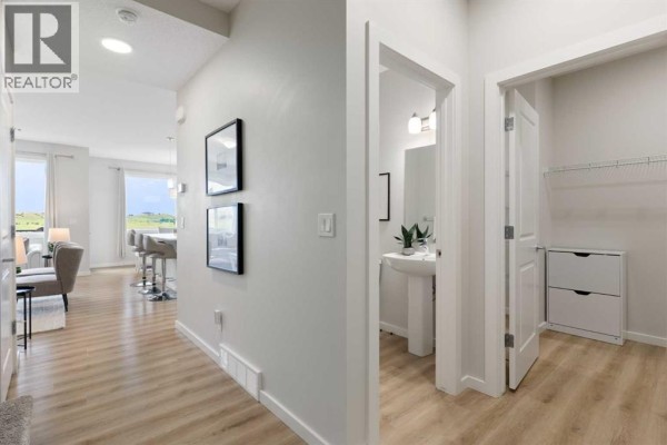 Kitchen island with white countertops and seating, stainless steel appliances, and white cabinetry. - 464 Lawthorn Way Se, Airdrie