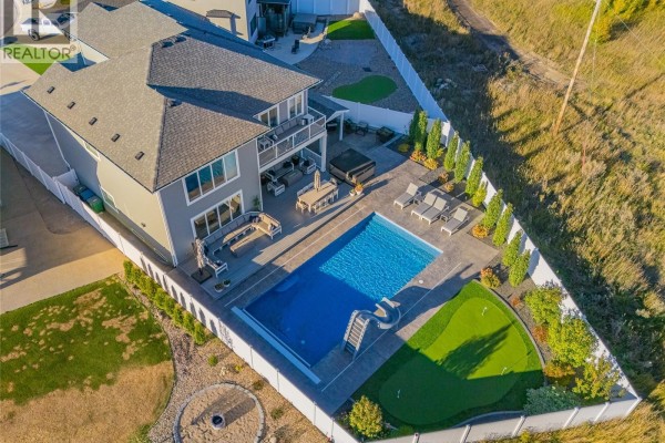 Aerial view of the backyard featuring a swimming pool, hot tub, patio furniture, and a small putting green. - 464 Woolf Bend, Saskatoon