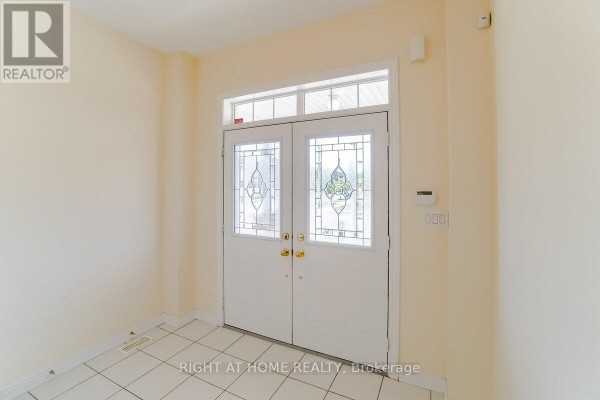 Interior view of the foyer with cream walls and tiled floor, facing double glass doors. - 4644 Doug Wright Drive, Burlington