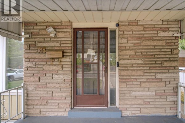Front door area of the house featuring a wooden door with glass panels and a mail slot on stone facade. - 465 Herkimer Street, Hamilton