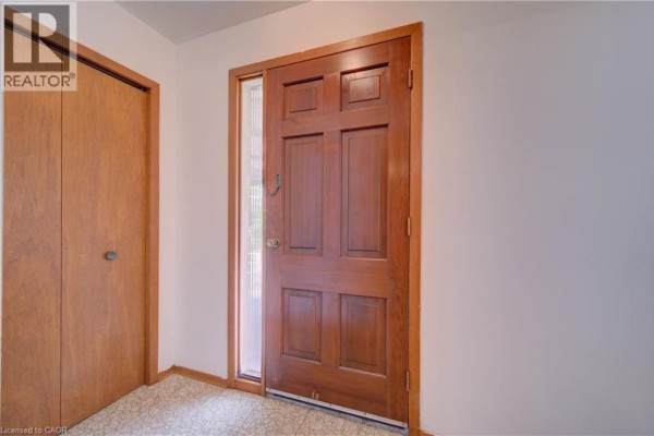 Interior entryway with a polished wooden door, sidelight window, and a closet with wooden doors. - 465 Herkimer Street, Hamilton