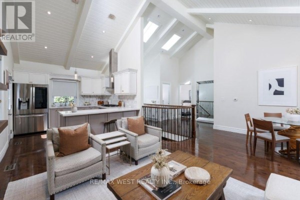 Living room and kitchen area with vaulted ceiling, fireplace, and breakfast bar. - 4653 Dundas Street W, Toronto