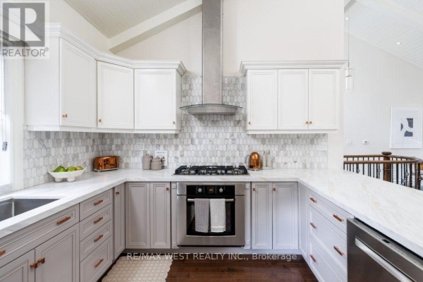 Modern kitchen with marble counters, tile backsplash, stainless steel gas range, and vaulted ceiling - 4653 Dundas Street W Toronto