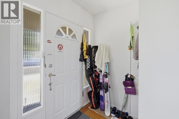 The entryway features a white door, skis, jackets, and a shoe rack. - 4656 Brentlawn Drive, Burnaby