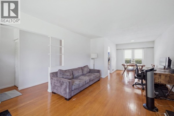 Open-concept living and dining area with a sofa, desk, and dining table. - 4656 Brentlawn Drive, Burnaby