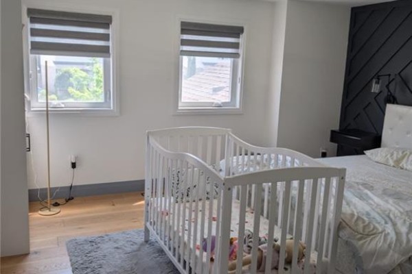 Living room with hardwood floors, a large window, a television, and many stacked boxes and baby items. - 466 Bankside Drive, Kitchener