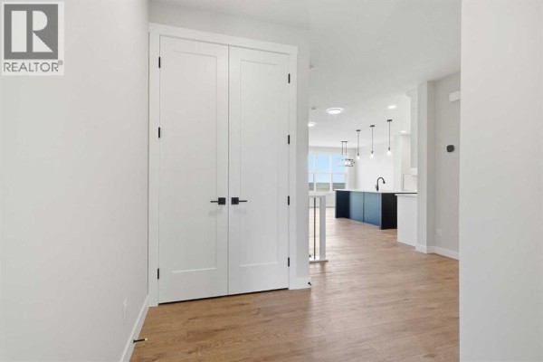Entryway with light-colored walls, round mirror, and wooden flooring - 467 Kinniburgh Loop, Chestermere