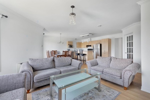 Living room and dining area with gray sofas, glass coffee table, dining set, kitchen, and french door. - 467 Rue De Cannes, Gatineau