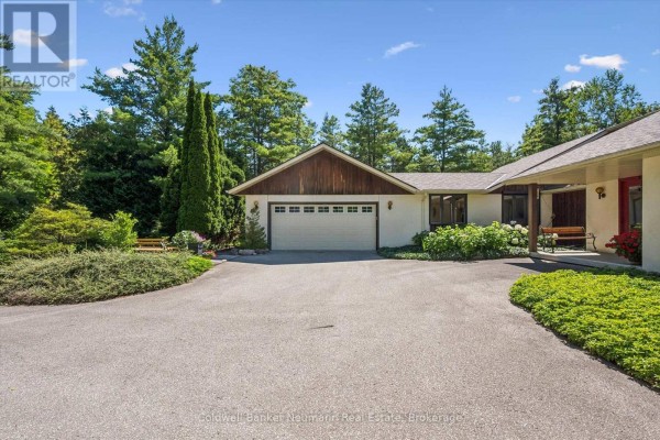 View of a white garage door with wood trim and a portion of a cream-colored house. - 4676 Concession 11 Road, Puslinch