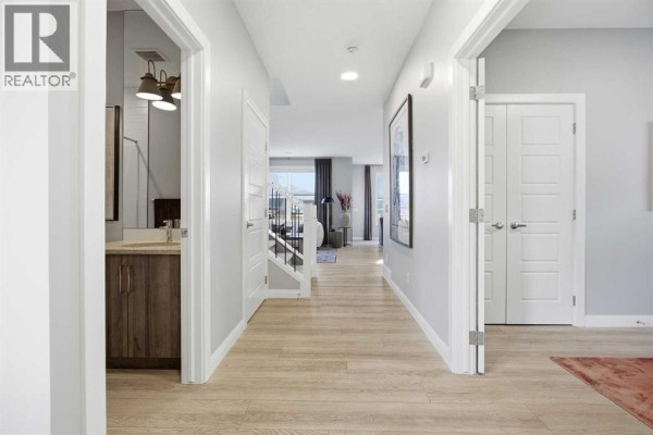 Interior entryway with light wood laminate flooring, white walls, and a white front door. - 468 Dawson Circle, Chestermere