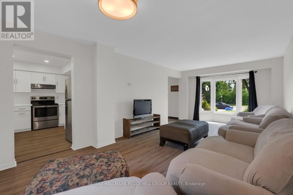 Living room with beige sectional sofa, ottoman, television, and large bay window. - 468 Grove Street E, Barrie