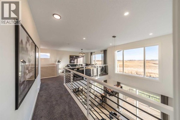 Second-floor hallway overlooks the open-concept living and dining areas below. - 468 Northern Lights Place, Langdon