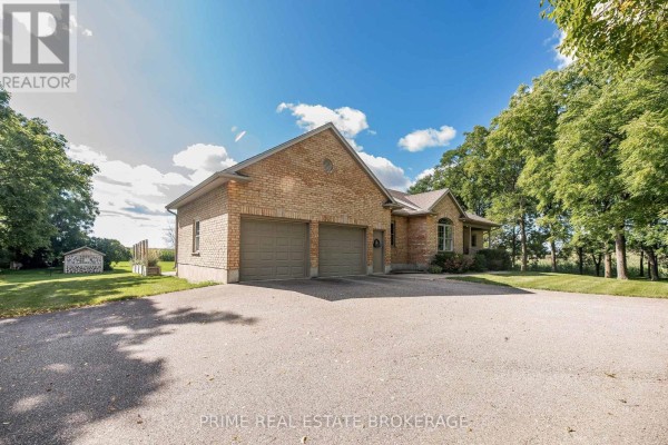 Side view of a brick house with a three-car garage and a shed on the lawn. - 46821 Mapleton Line, Aylmer