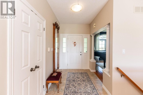 Home entryway with tiled floor, white doors, bench, rug, and a staircase. - 46821 Mapleton Line, Aylmer