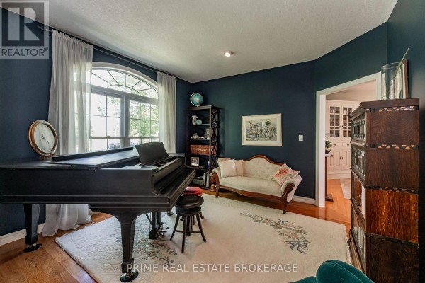Living room with a black grand piano, ornate couch, dark blue walls, and arched window. - 46821 Mapleton Line, Aylmer