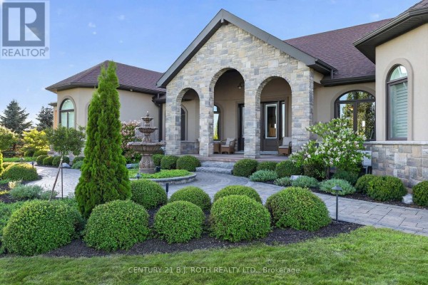 A manicured front yard with a fountain, tiered shrubs, and a stone-arched entryway. - 4688 5th Side Road, Essa