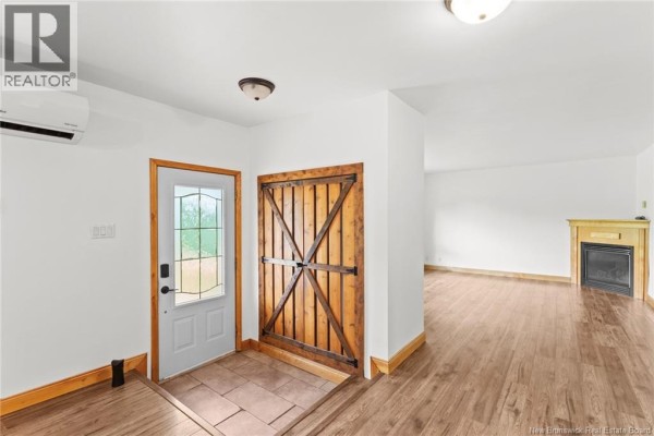 Interior entryway with a white door, a rustic wooden barn door, stone tile floor, and wood laminate flooring. - 469 Upton St, Minto