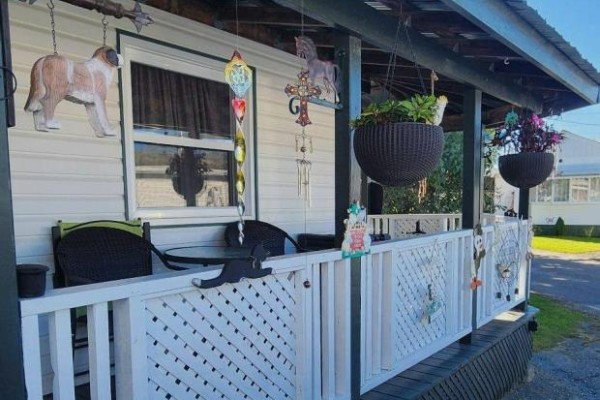 Close-up of the porch with chairs, table, hanging plants, and decorative railing. - 47 - 25 County Road 31 Road, South Dundas