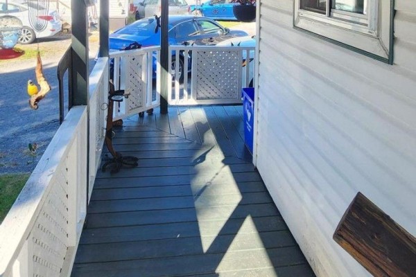 View down the wooden porch with shadows and a doorway to the right. - 47 - 25 County Road 31 Road, South Dundas