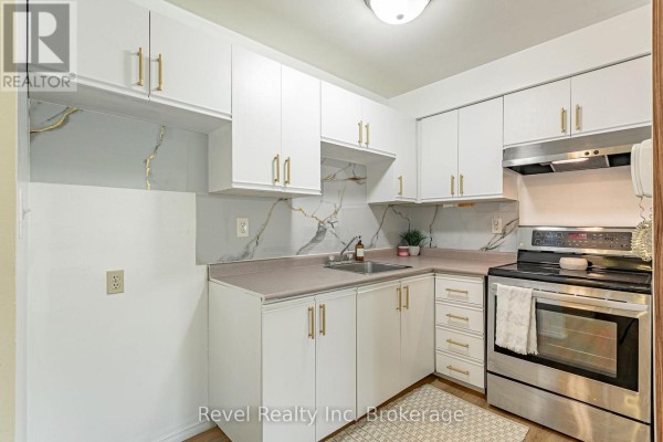 A compact kitchen with white cabinets, gold hardware, stainless steel appliances, and a marble backsplash. - 47 - 56 Hiawatha Road, Woodstock