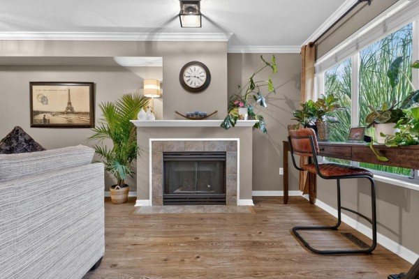 Living room with a fireplace, desk, large window, and plants. - 47 18883 65 Street, Surrey