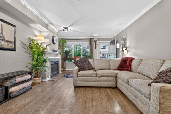 Living room with a sectional sofa, fireplace, desk, and entryway visible. - 47 18883 65 Street, Surrey