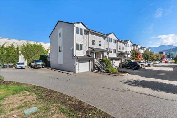 Side view of a townhouse complex with garages and parked cars. - 47 5950 Vedder Road, Vedder Crossing, Chilliwack
