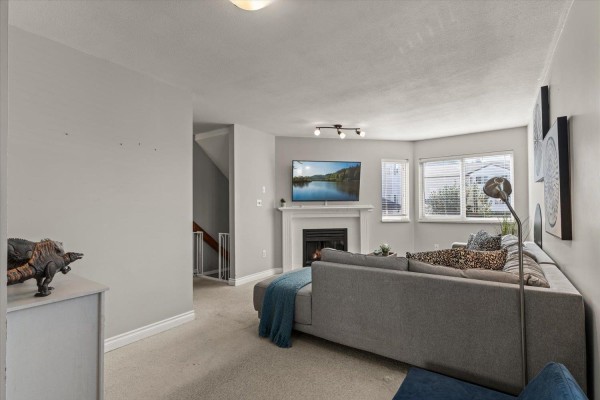 Living room with sofa, fireplace, television, and stairs to upper level. - 47 5950 Vedder Road, Vedder Crossing, Chilliwack