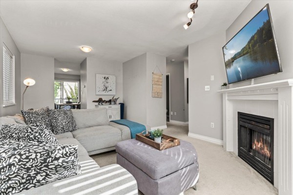 Living room with fireplace, sofa, ottoman, and doorway to dining area. - 47 5950 Vedder Road, Vedder Crossing, Chilliwack
