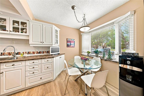 Kitchen nook with a round glass-top dining table, four white chairs, and white cabinetry. - 47 Abington Road, Winnipeg