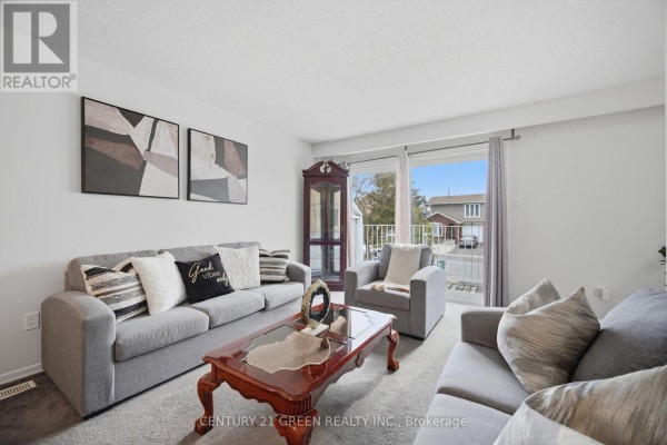 Living room with two gray sofas, a chair, a wooden cabinet, and large sliding glass doors. - 47 Ashford Court, Brampton