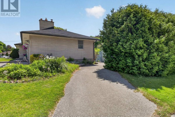 Asphalt driveway leading past the side of the house towards a backyard area. - 47 Churchill Avenue, Oshawa