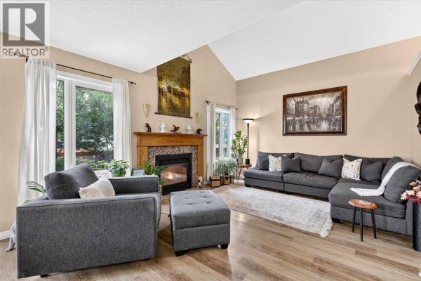 Living room featuring a large sectional sofa, ottoman, and a gas fireplace. - 47 Cimarron Hill, Okotoks
