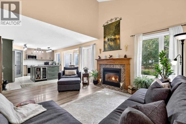 Living room with a fireplace, a chaise lounge, and an open-concept kitchen view. - 47 Cimarron Hill, Okotoks