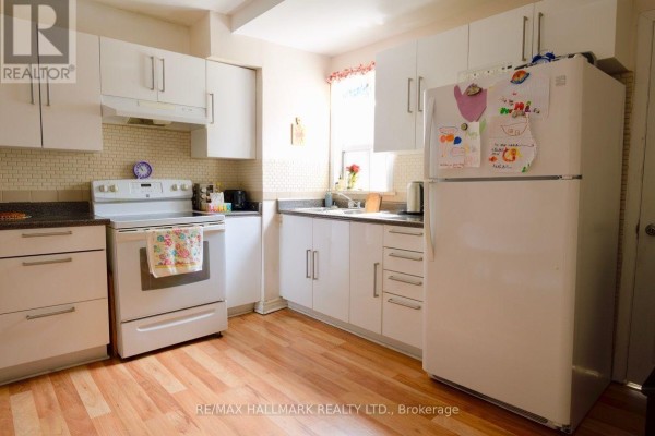 Kitchen with white cabinets, white refrigerator, white stove, and light wood floors. - 47 Dentonia Park Avenue, Toronto