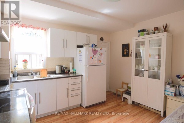 Kitchen with white cabinets, white refrigerator, glass-front cabinet, and light wood floors. - 47 Dentonia Park Avenue, Toronto