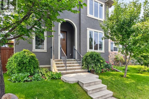 Close-up of the front entrance of a grey stucco house with stone accents and large windows. - 47 Elgin Meadows Road Se, Calgary