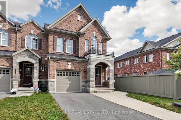 Close-up exterior view of a brick townhouse with stone accents and an attached garage. - 47 Goodsway Trail, Brampton
