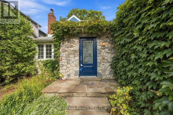 Close-up of the blue front door with decorative glass, set in a stone facade. - 47 Harding Boulevard, Toronto