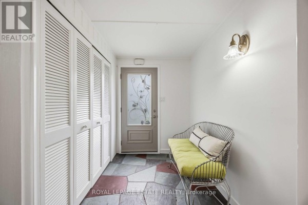 Entranceway with white louvered closet doors, green cushioned bench, and multi-colored slate floor. - 47 Harding Boulevard, Toronto