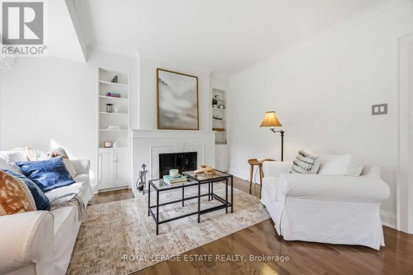 Living room with white couches, fireplace, built-in shelving, and a patterned area rug. - 47 Harding Boulevard, Toronto
