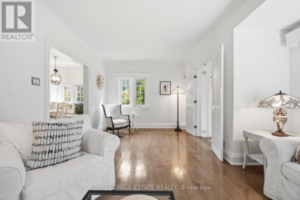 Living room with white furniture, hardwood floors, large windows, and a view into another room. - 47 Harding Boulevard, Toronto