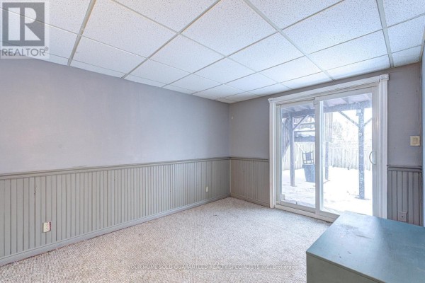 Interior basement room with carpet, grey paneled wainscoting, and a sliding glass door to the backyard. - Bsmt - 47 Hewitt Crescent, Ajax