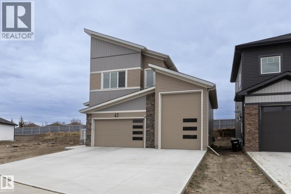 Living room with brown leather sofa, dark side table, and view into the kitchen. - 47 Hull Wynd, Spruce Grove