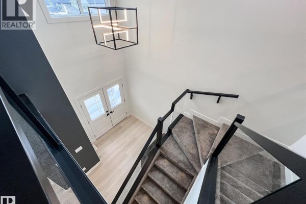 Modern two-story house exterior with grey and tan siding and two garage doors. - 47 Hull Wynd, Spruce Grove