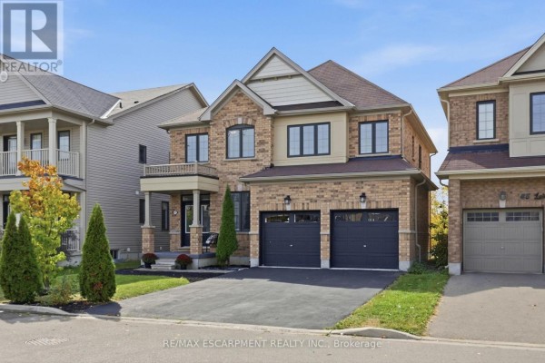 Two-story brick house with a double garage and balcony under a daytime sky. - 47 Larry Crescent, Haldimand