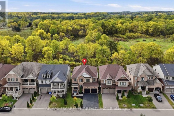 Aerial view of a suburban street with houses backing onto a wooded area. - 47 Larry Crescent, Haldimand